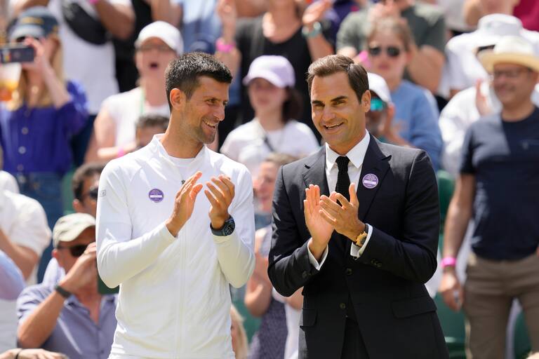 Novak Djokovic y Roger Federer aplauden durante el festejo del centenario de la Cancha Central de Wimbledon, el domingo 3 de julio de 2022
